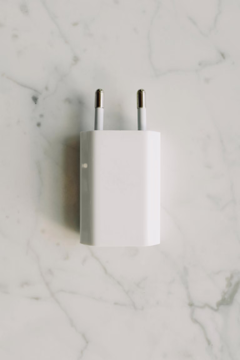 A minimalist white power adapter placed on a marble surface, showcasing simplicity and modern design.